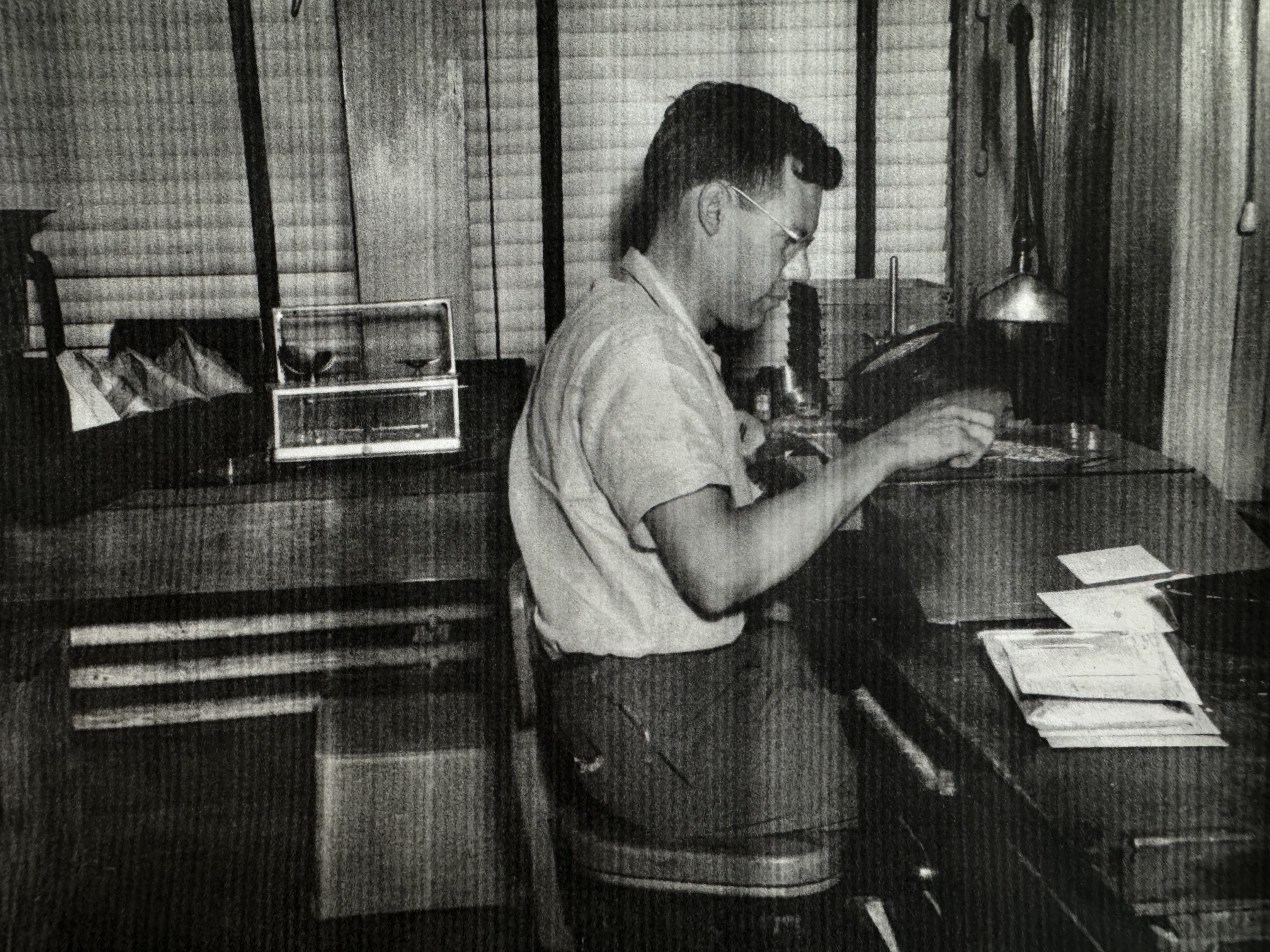 Jake Hulsey at his testing bench, sorting seed beside a lamp and a stack of seed envelopes